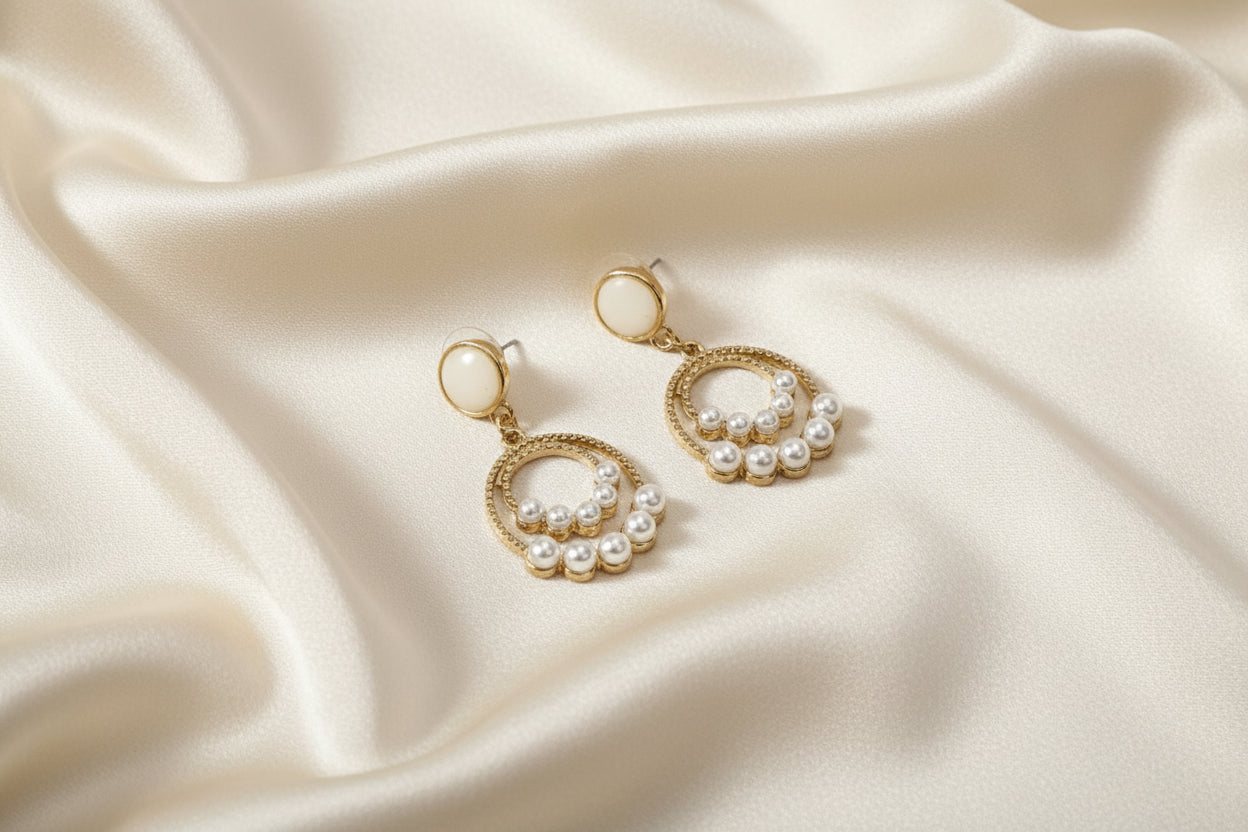 Pearl earrings on a soft beige fabric background