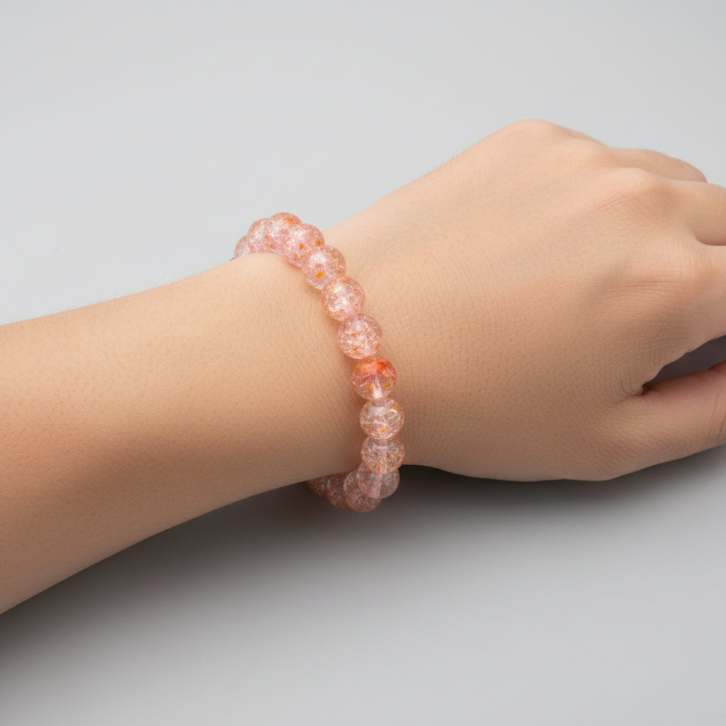Hand wearing a pink beaded bracelet on a light gray background