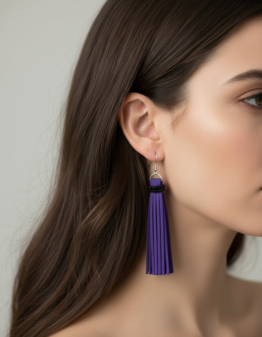 Woman wearing handmade long purple faux leather tassel earrings with crystal bead accents