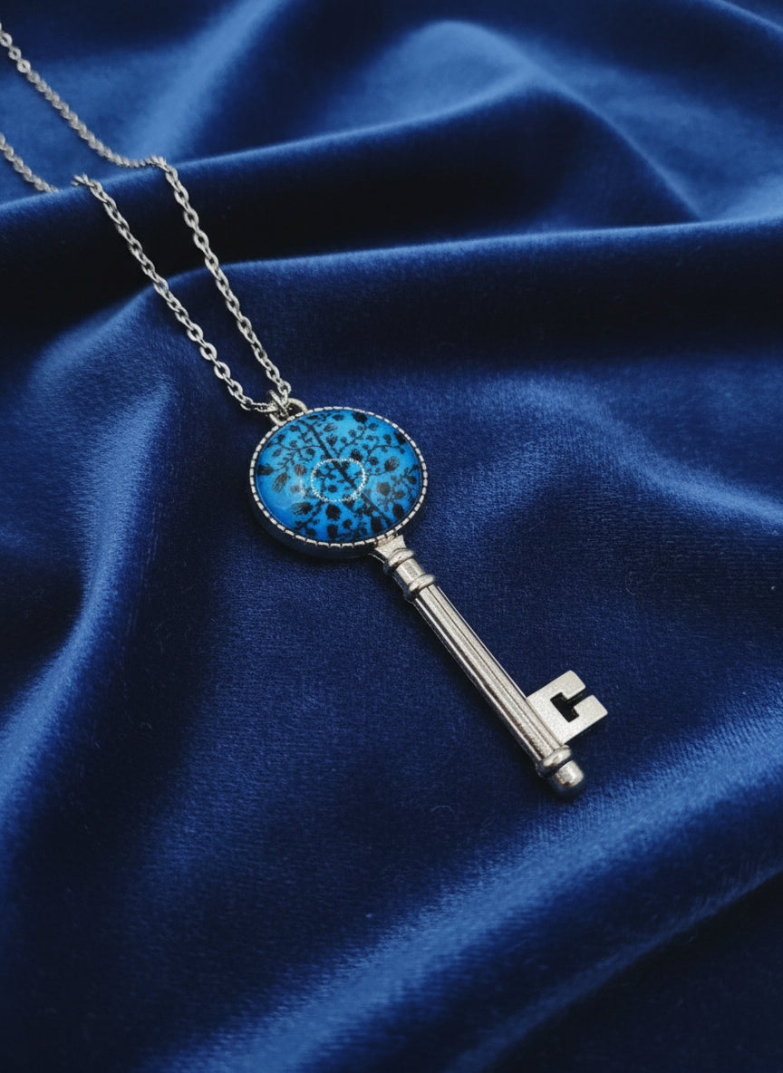 Key-shaped pendant with blue stone on a blue fabric background
