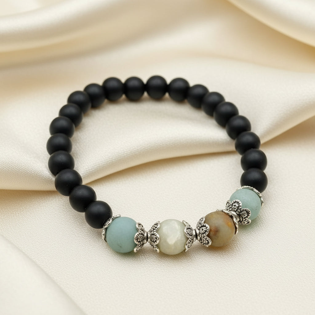 A bracelet featuring a series of matte black onyx beads and varying shades of matte amazonite gemstone beads, with a decorative metal bead and a lobster clasp closure.