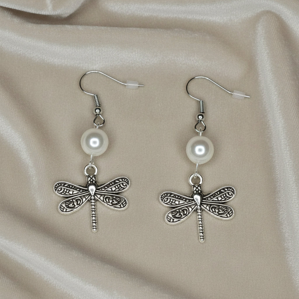 Antique Silver DragonFly Dangle Earrings laying on a soft cloth