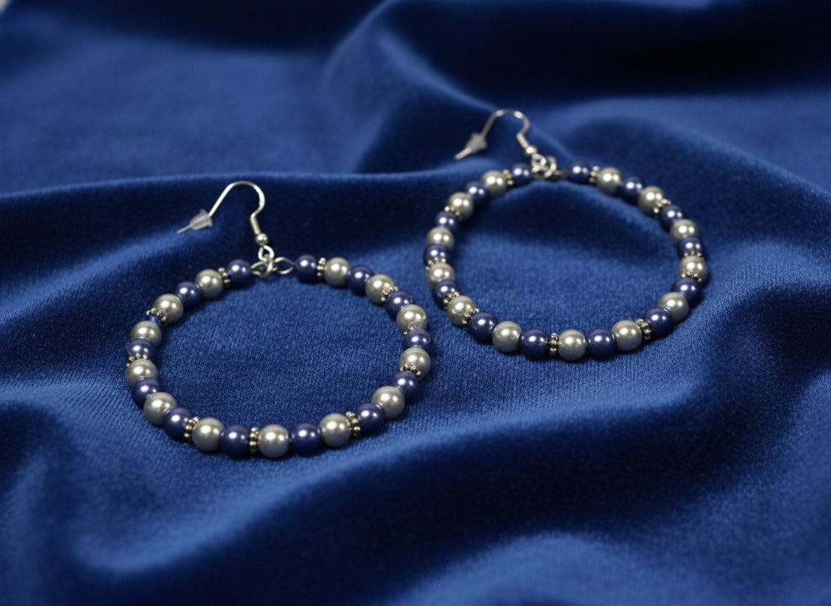 Aluminum wire hoop earrings with blue and silver beads lying on a soft cloth