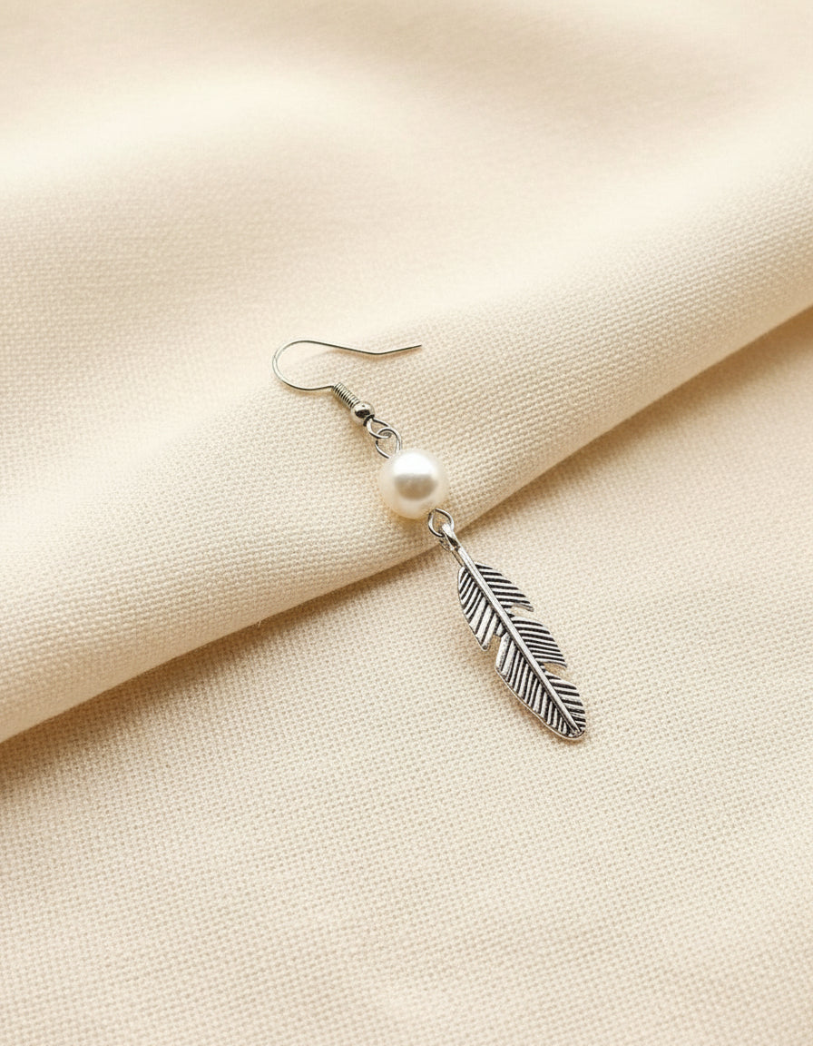 Earring with pearl and feather design on beige fabric