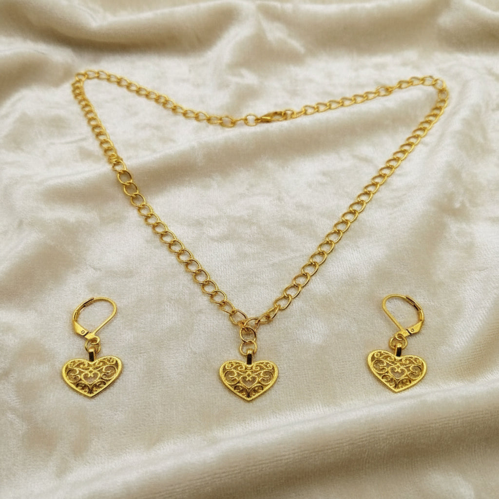 Gold heart necklace and earrings lying on a soft cloth with elegant lighting