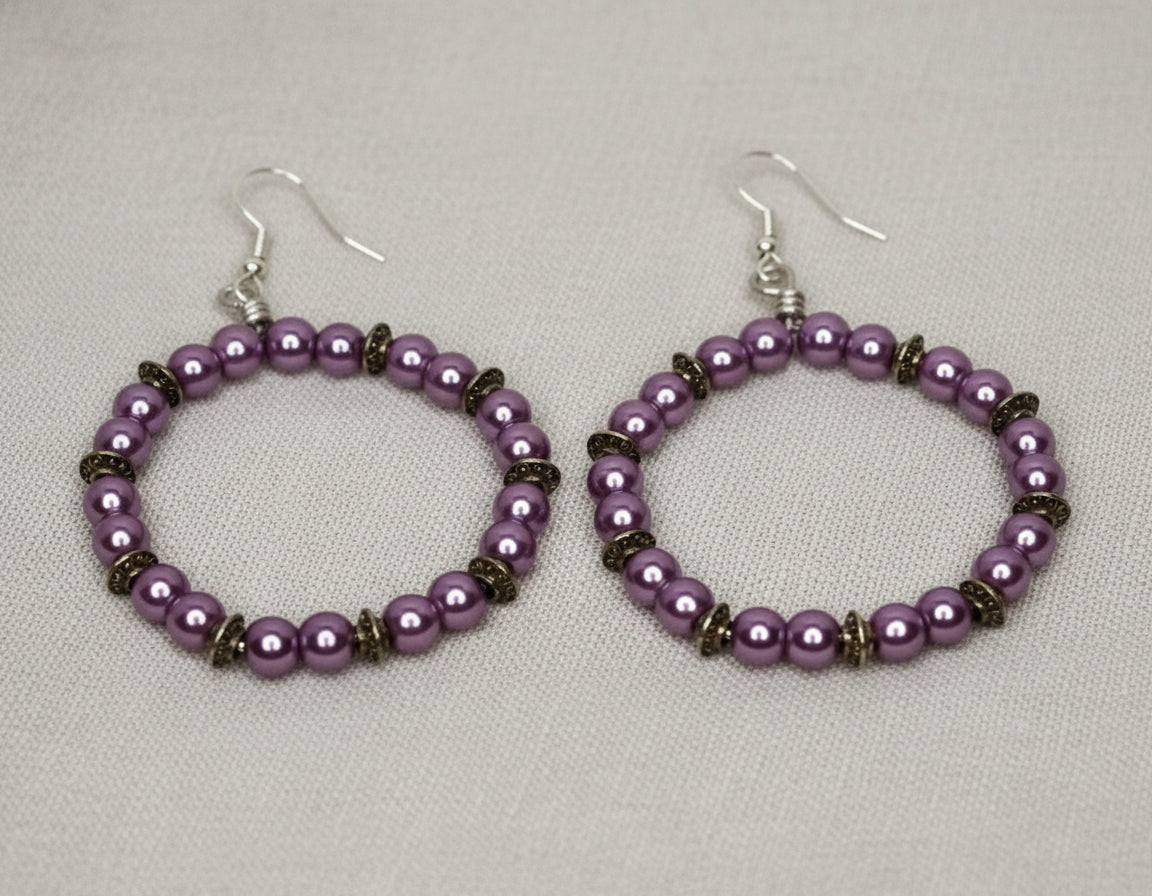 Lavender aluminum wire hoop earrings lying on a soft cloth