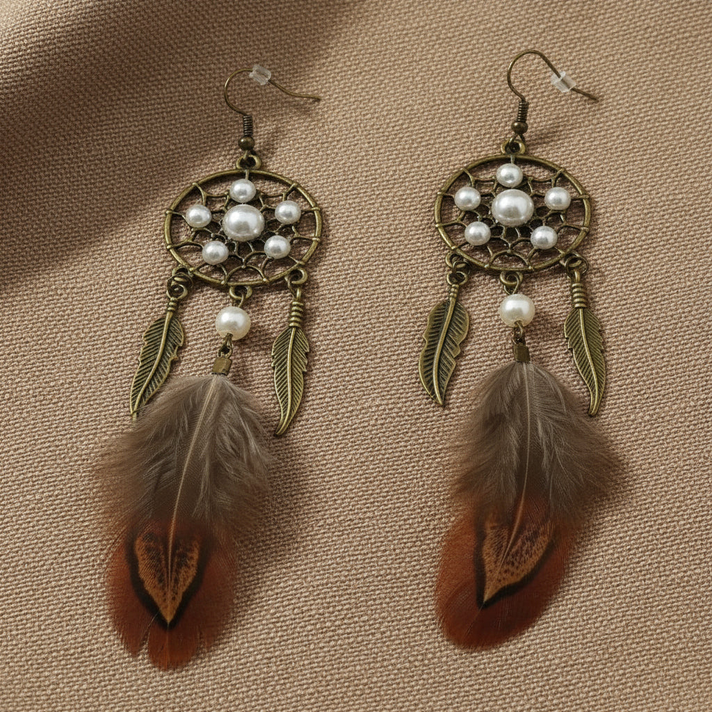 Pheasant feather dream catcher earrings with pearl beads lying on a soft cloth