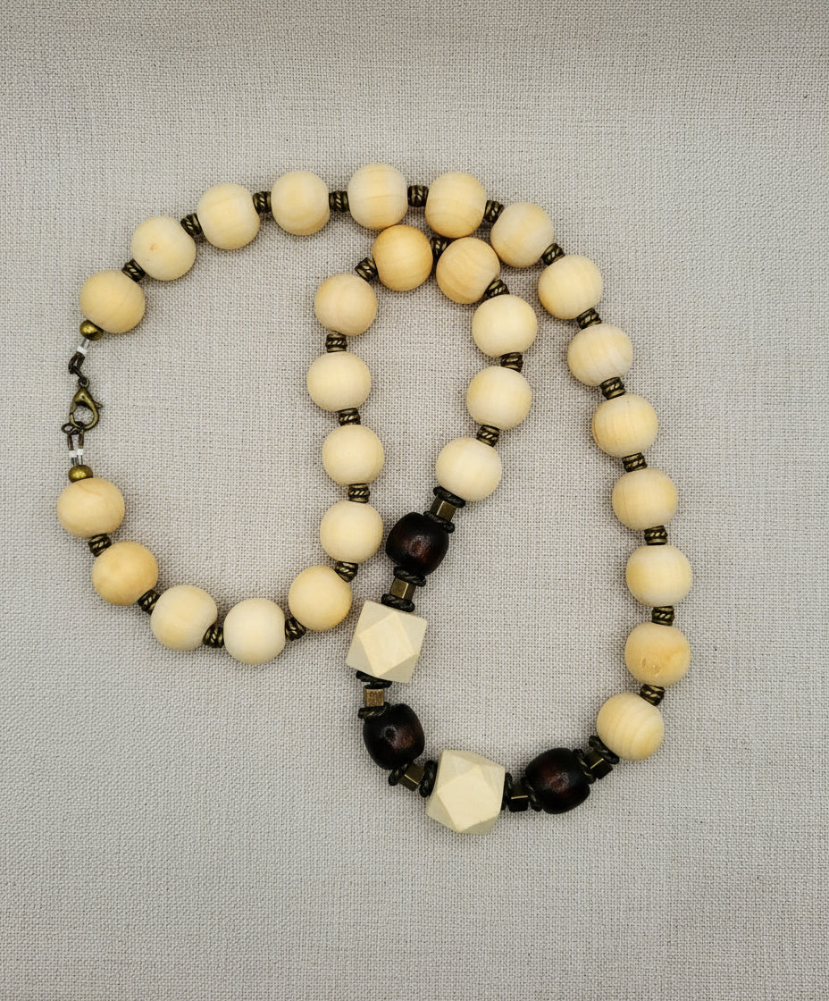 Handmade natural wood bead necklace lying on a soft cloth, showing its variety of bead shapes and textures