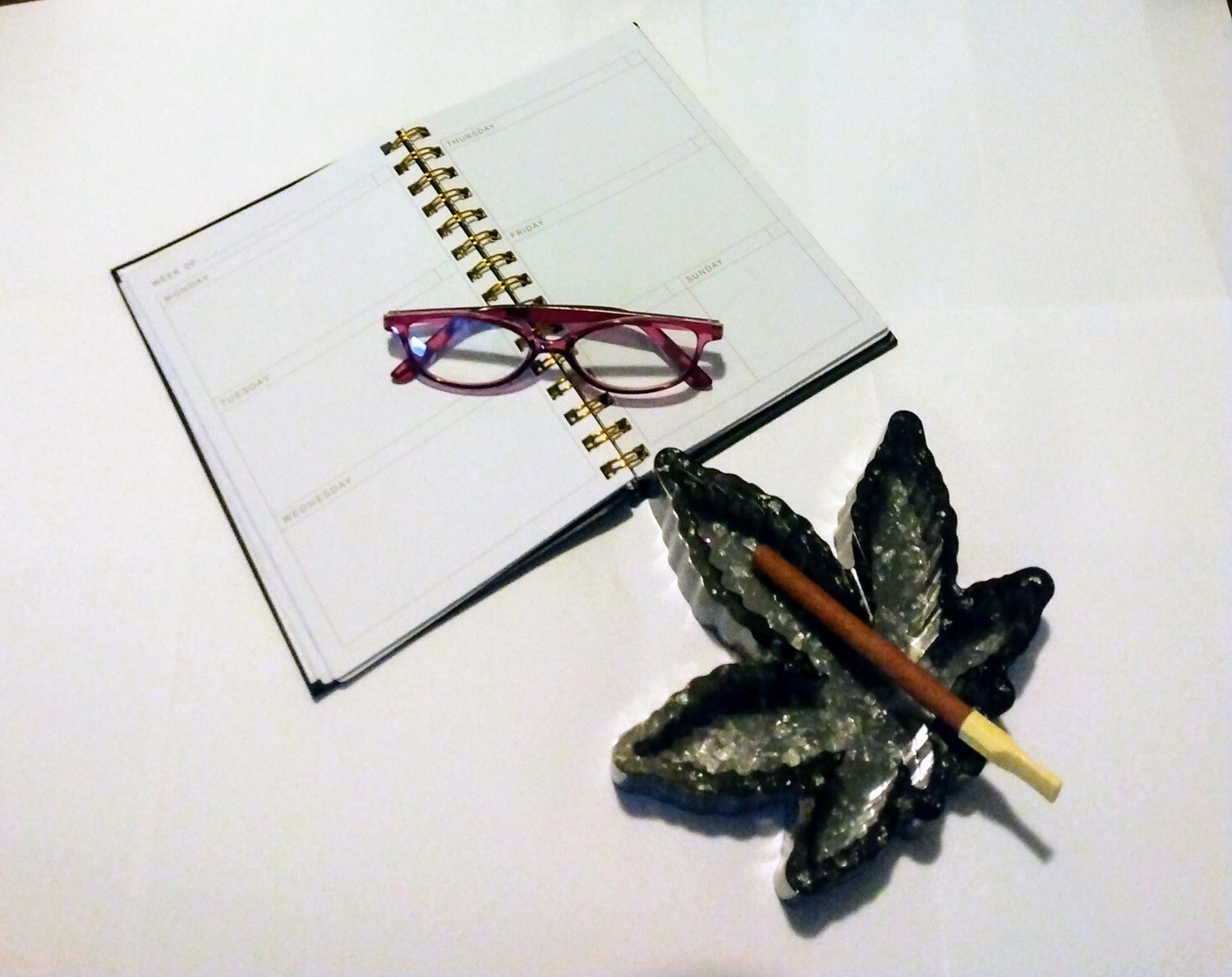 resin marijuana ashtray with a spiral notebook and reading glasses