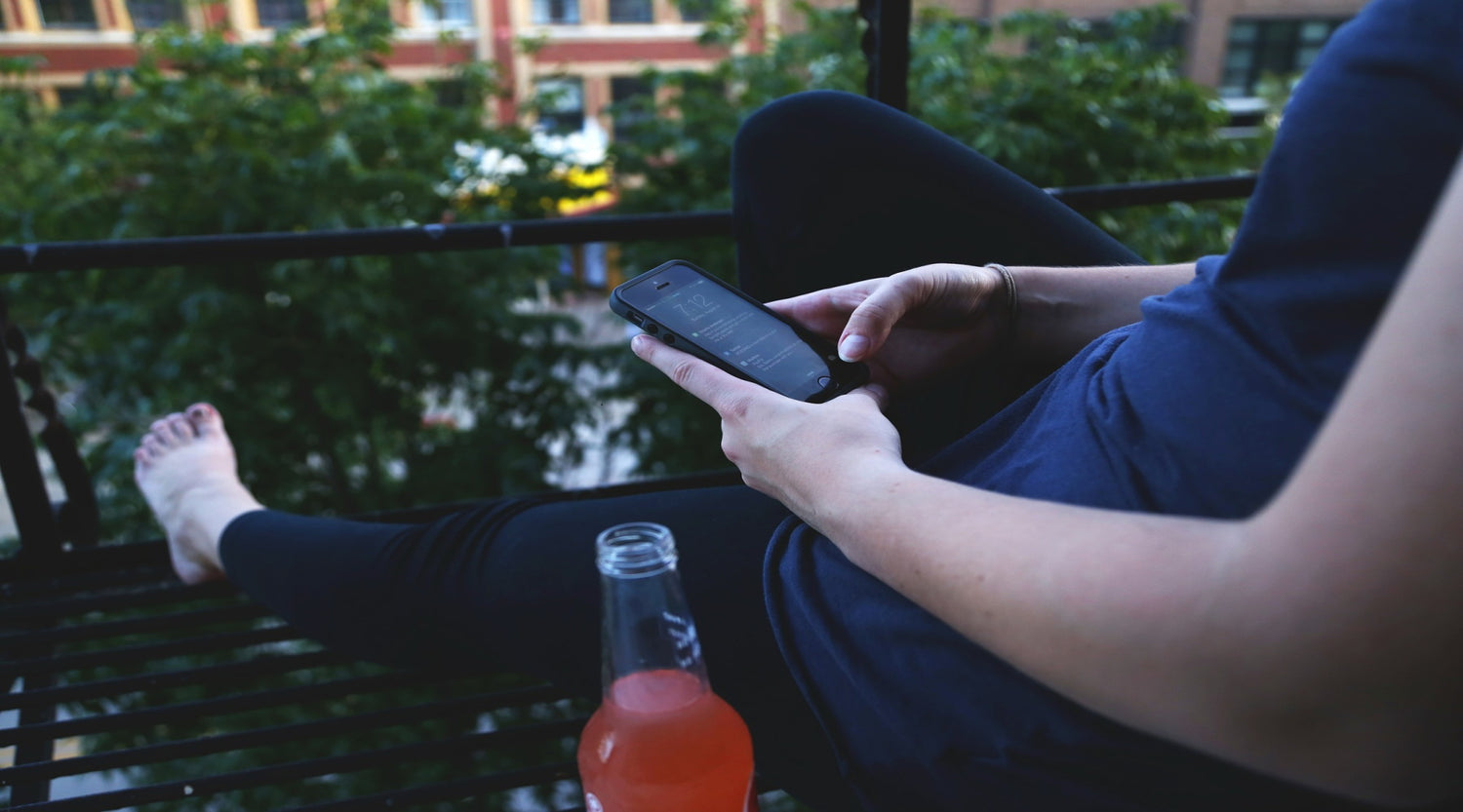 Woman sitting using a iphone with a polycarbonate iphone case