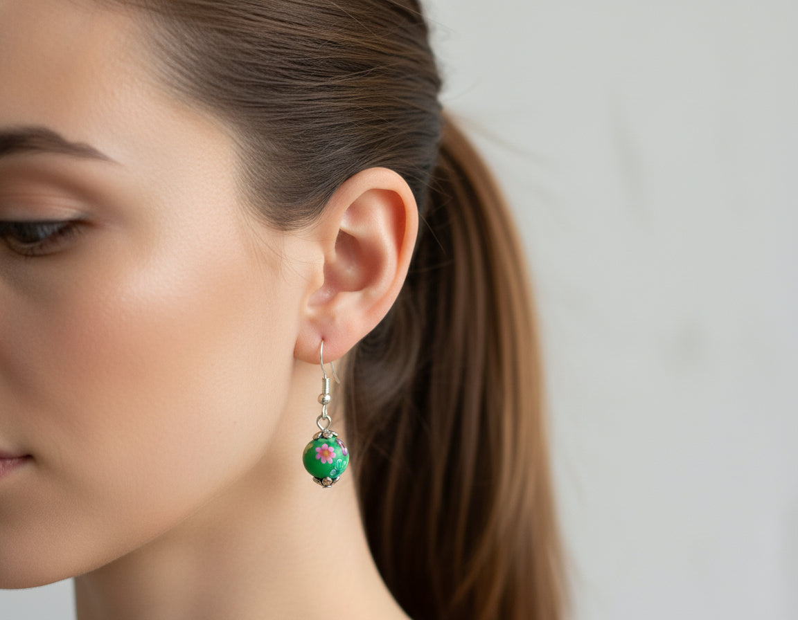 Woman wearing handmade polymer clay dangling earrings with floral stoppers