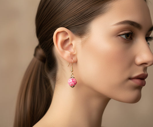 Woman wearing handmade polymer clay dangling earrings with floral stoppers