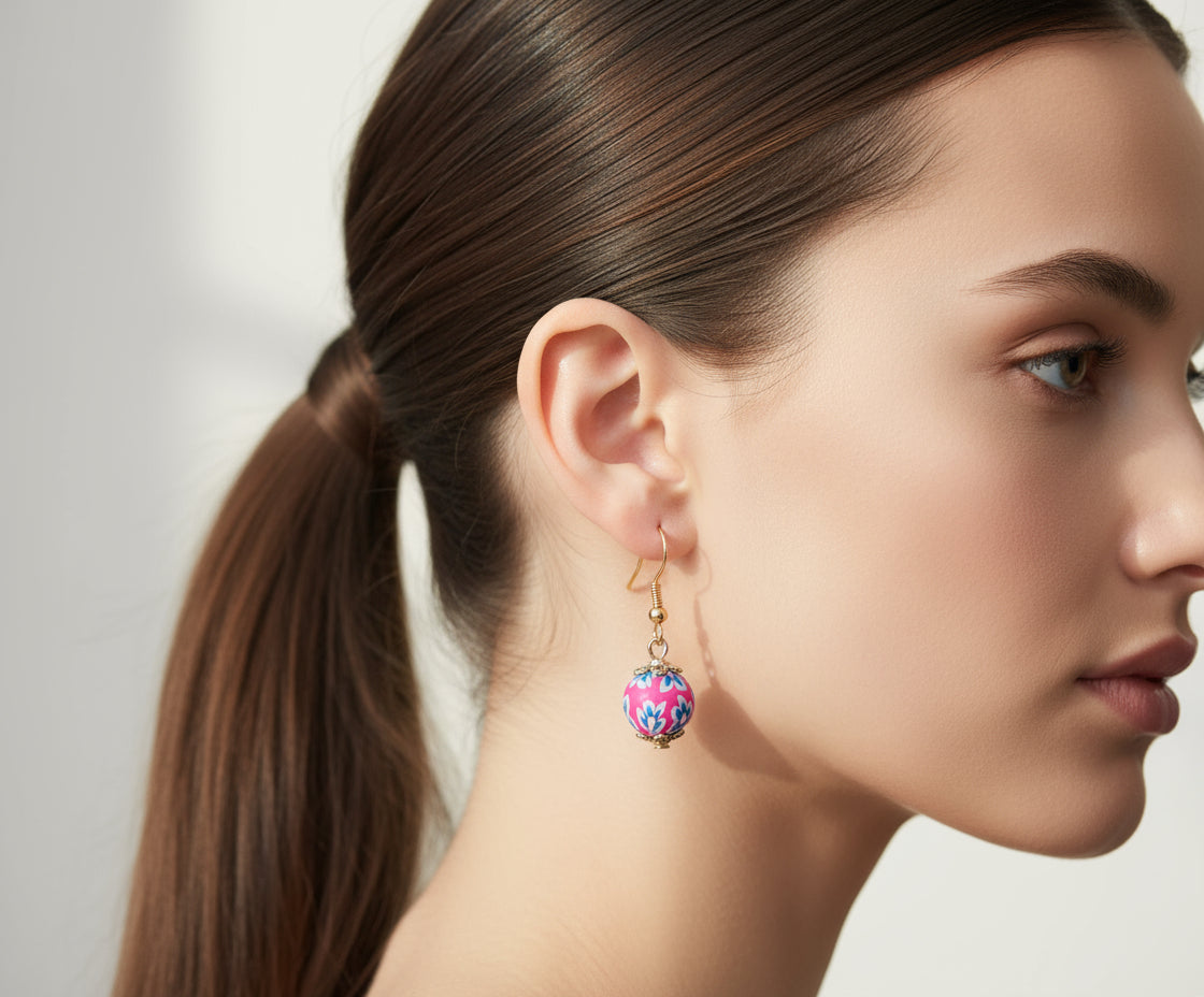 Woman wearing handmade polymer clay dangling earrings with floral stoppers