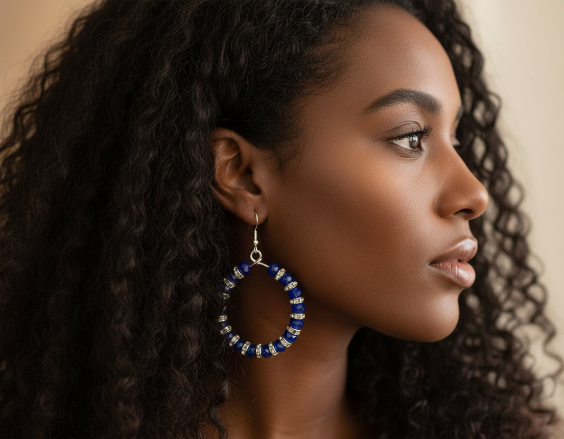 Woman wearing a blue beaded hoop earring with a neutral background
