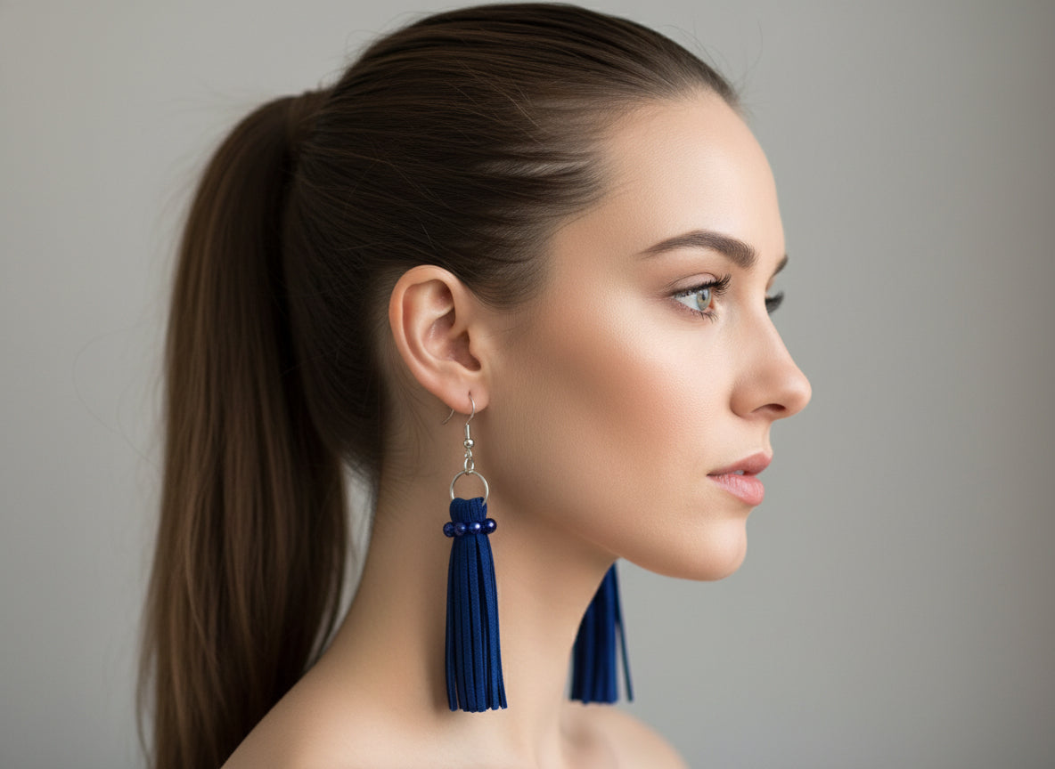 Woman wearing blue tassel earrings against a neutral background