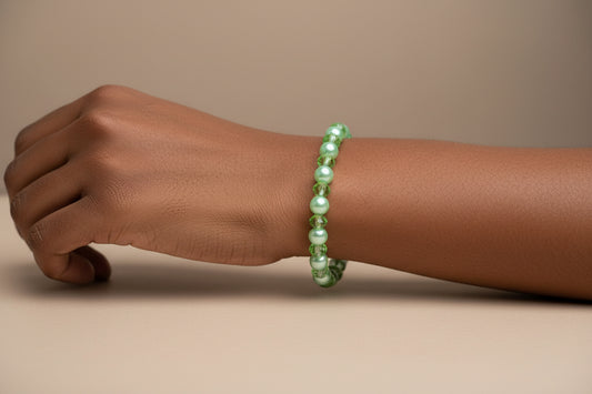 Green beaded bracelet on a wrist against a beige background