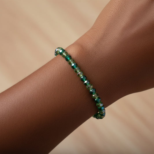 Green beaded bracelet on a wrist against a beige background