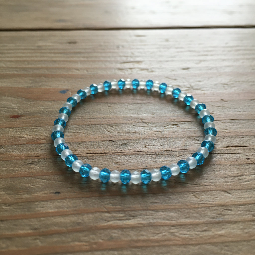 Beaded bracelet with blue and white beads on a wooden surface