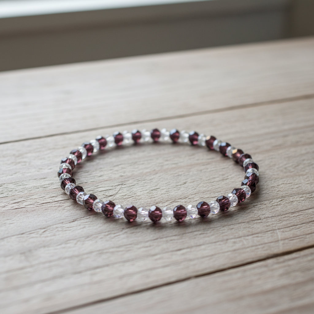 Beaded bracelet with purple and clear beads on a wooden surface