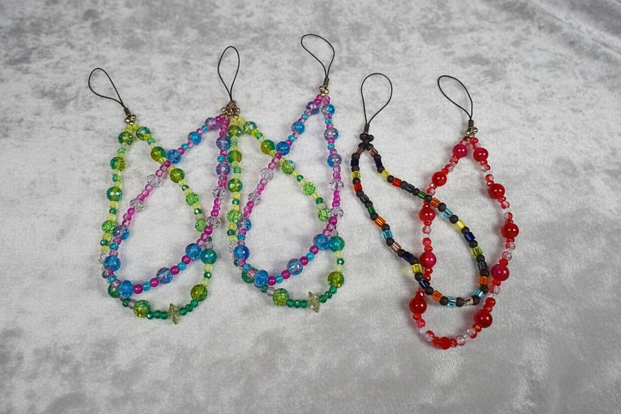 Four colorful beaded phone straps on a white background