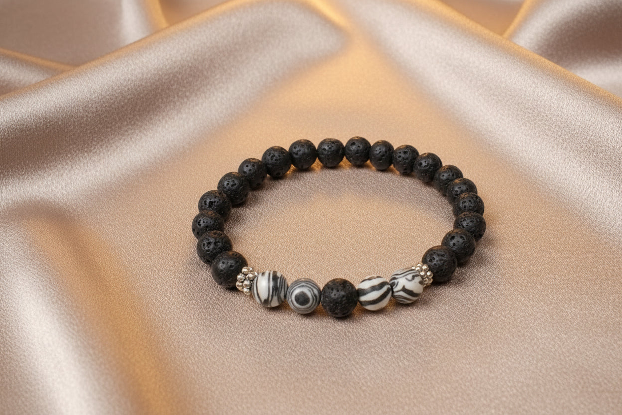 Black beaded bracelet with decorative beads on a beige fabric background