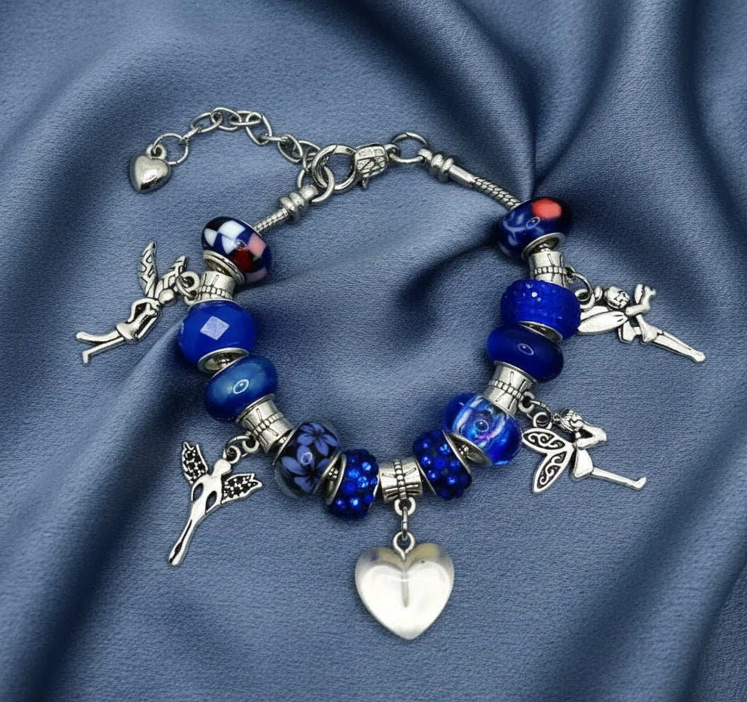 Bracelet with blue beads and fairy charms on a blue fabric background