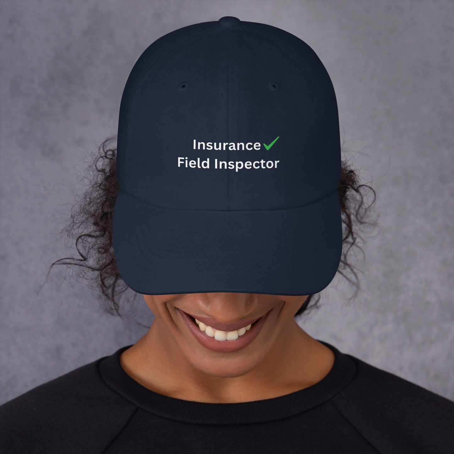Person wearing a navy blue cap with 'Insurance Field Inspector' text on a gray background
