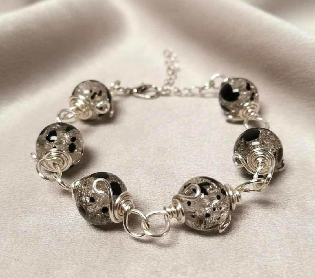 Silver bracelet with textured beads on a light fabric background