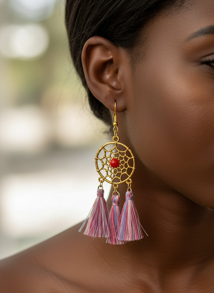 Gold earrings with red center and colorful tassels worn by a person.