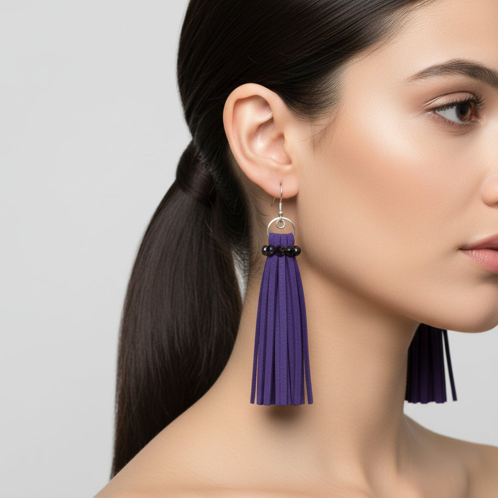 Woman wearing purple tassel earrings on a plain background