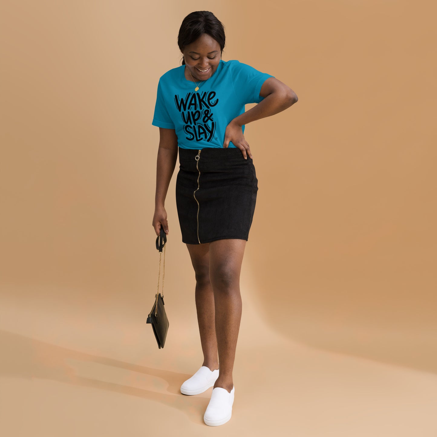 Woman wearing a blue t-shirt with text, black skirt, and white shoes on a beige background