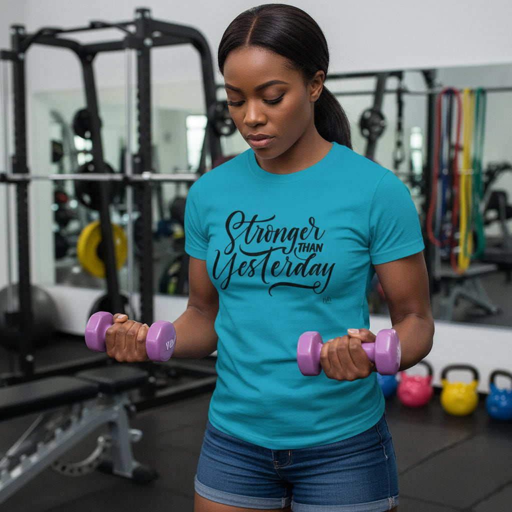 Woman lifting weights in a gym wearing a blue t-shirt with 'Stronger Than Yesterday' text.