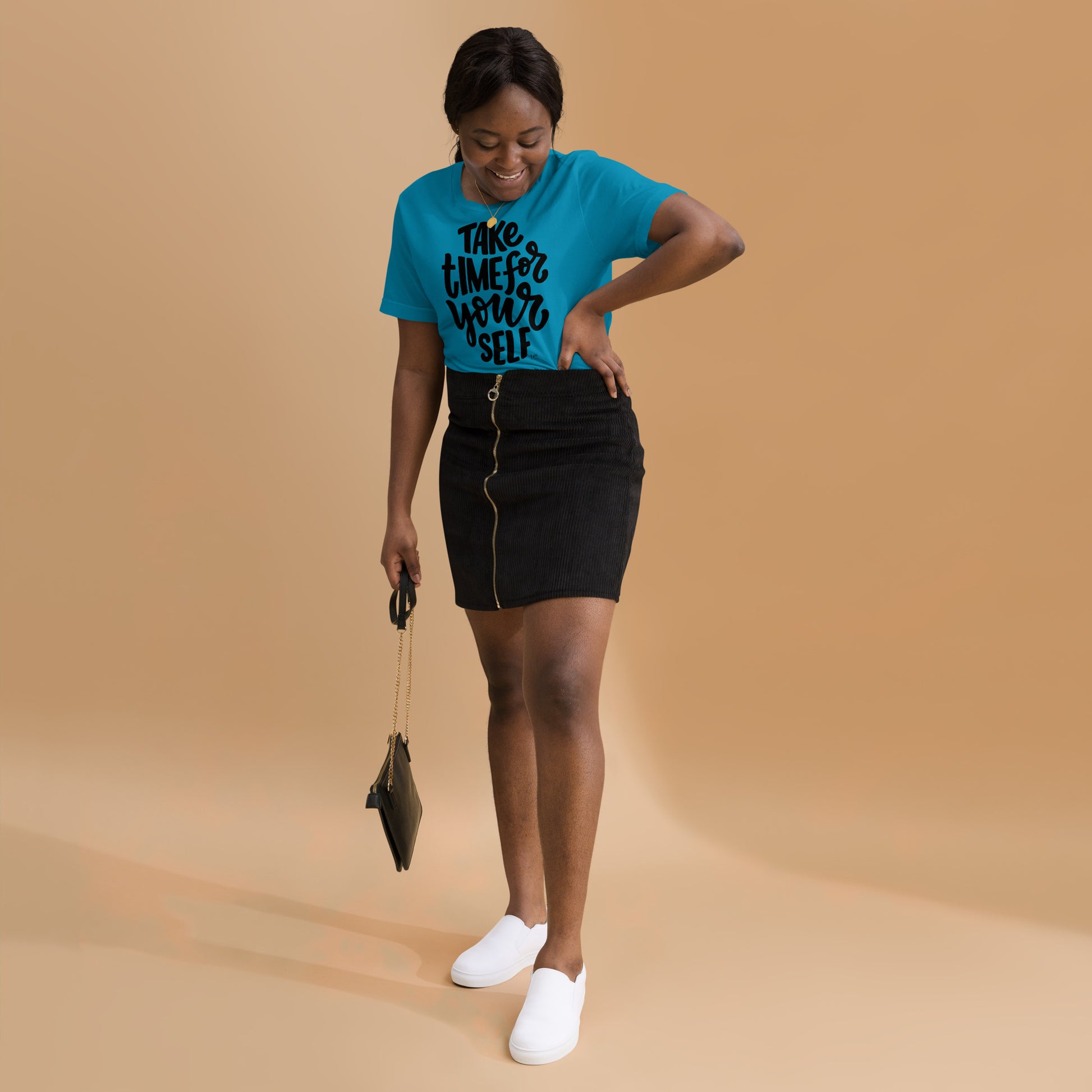 Woman wearing a blue t-shirt with text and black skirt on a beige background