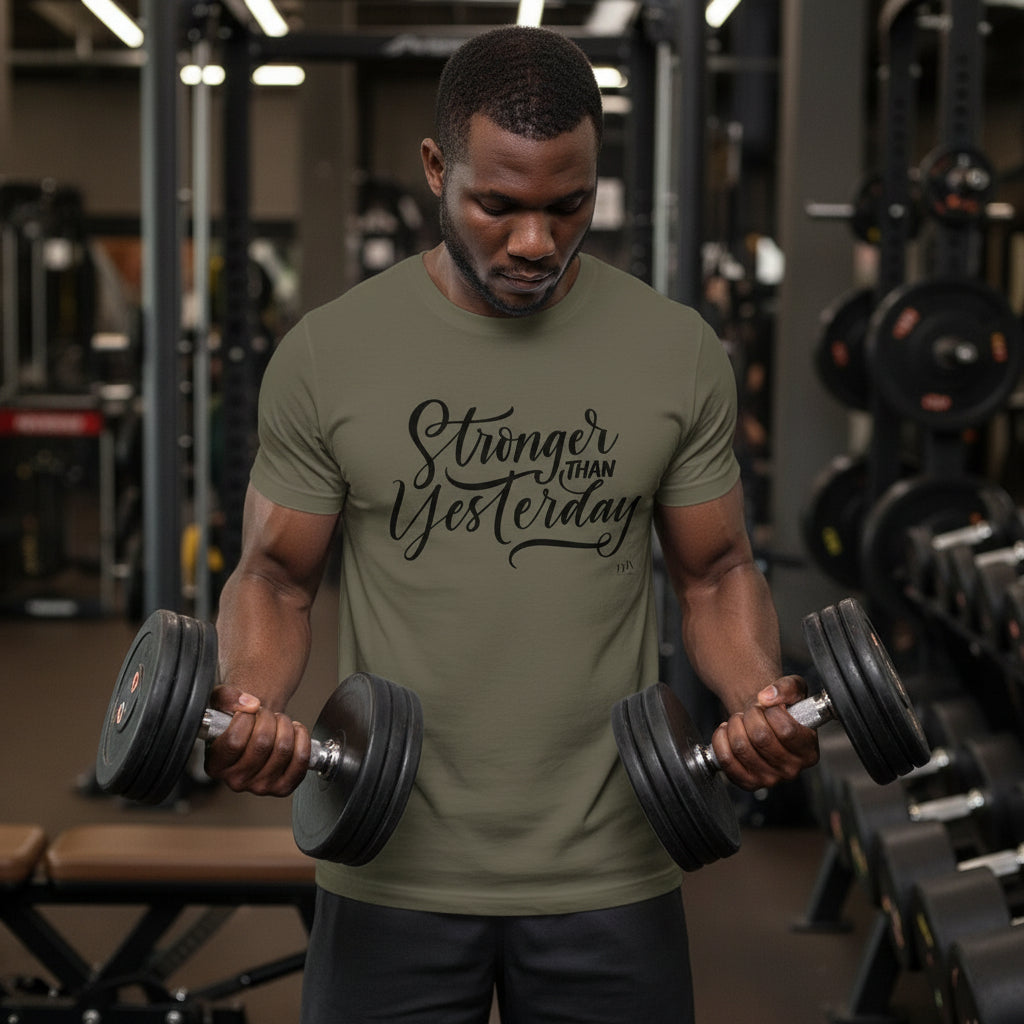 Man lifting weights in a gym wearing a green t-shirt with motivational text.