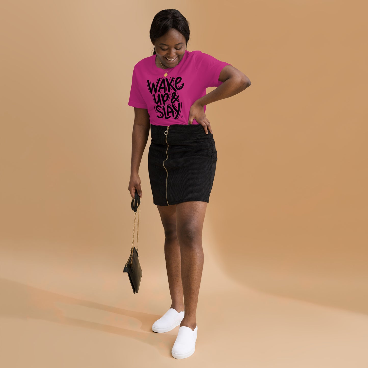 Woman wearing a pink t-shirt with text, black skirt, and white shoes on a beige background