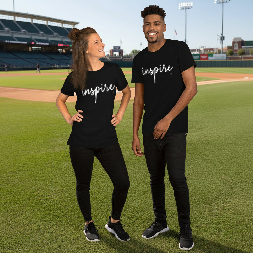 Two people wearing black t-shirts with 'inspire' on a baseball field.