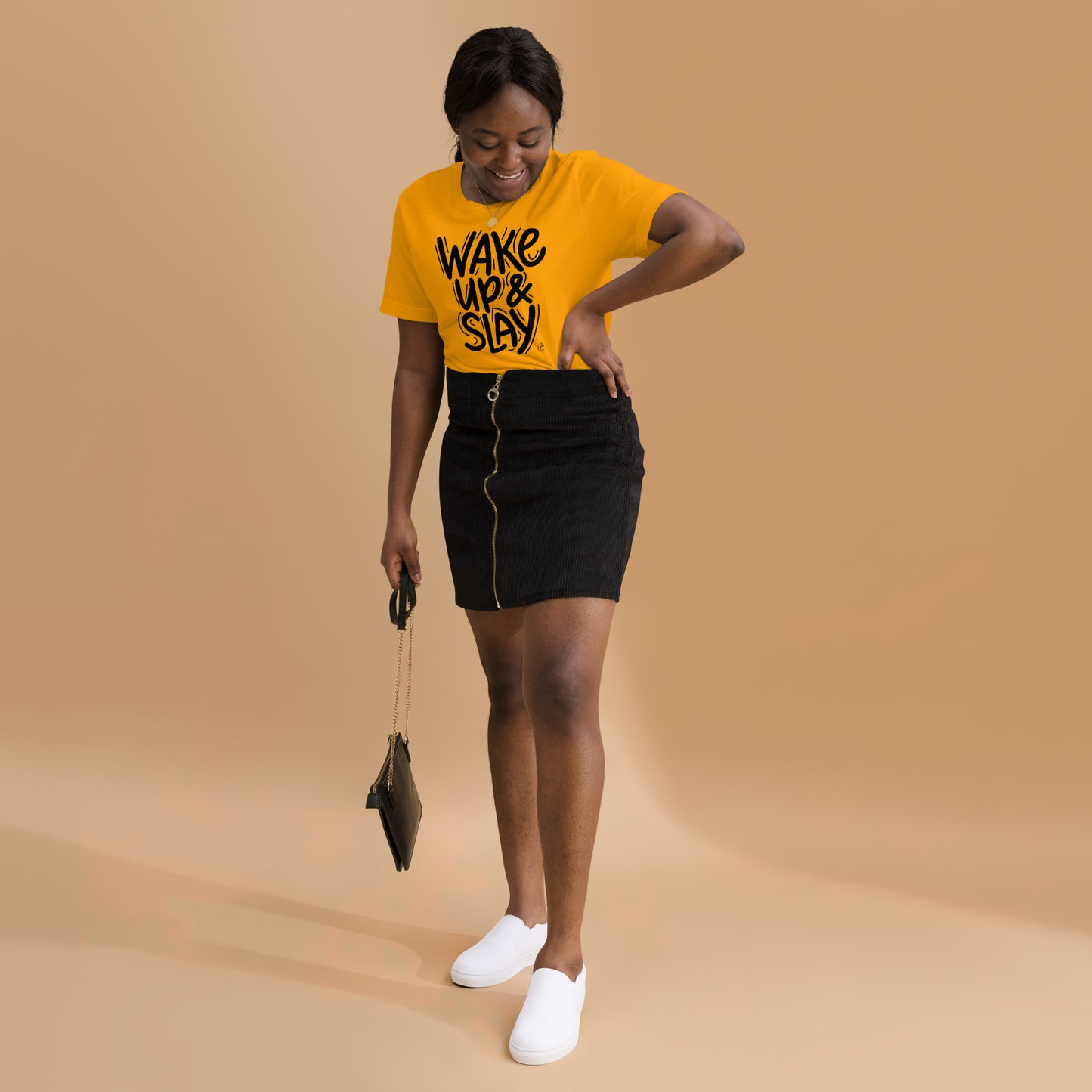 Woman wearing a yellow t-shirt with text, black skirt, and white shoes on a beige background
