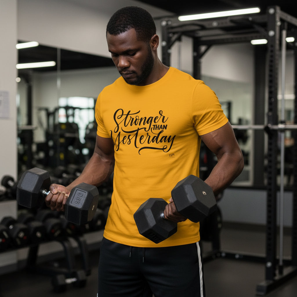 Man in a gym wearing a yellow t-shirt with 'Stronger Than Yesterday' text, holding dumbbells.
