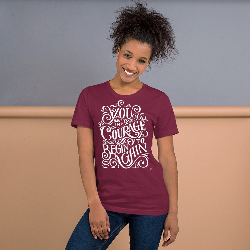 Woman wearing a maroon t-shirt with motivational quote on a beige and gray background