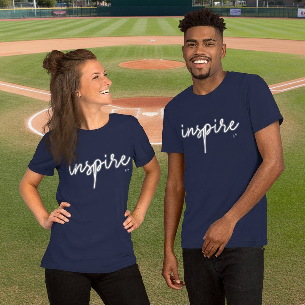 Two people wearing navy blue 'inspire' t-shirts on a baseball field.