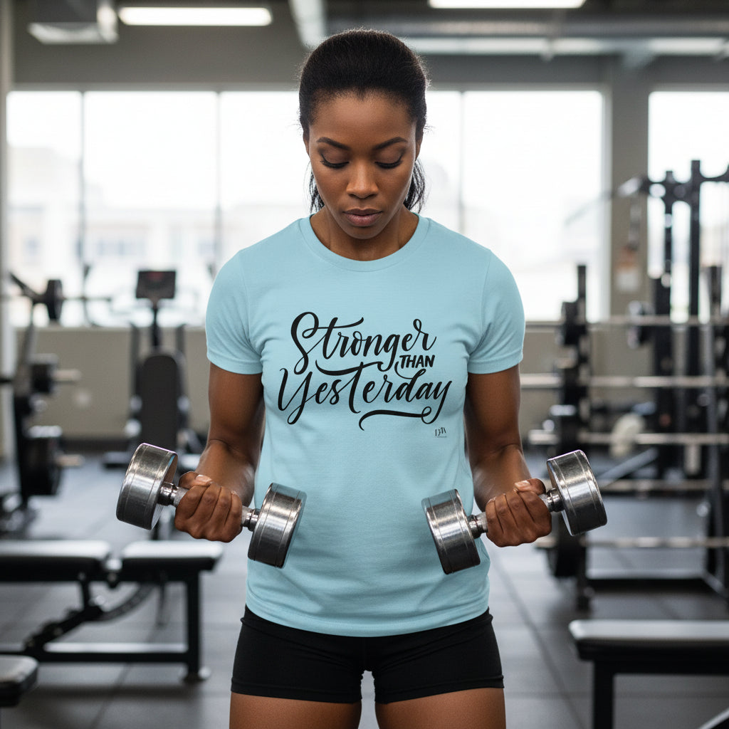 Woman lifting weights in a gym wearing a light blue t-shirt with 'Stronger Than Yesterday' text.