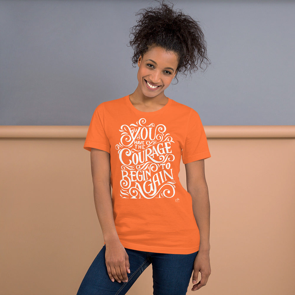 Woman wearing an orange t-shirt with motivational quote against a neutral background
