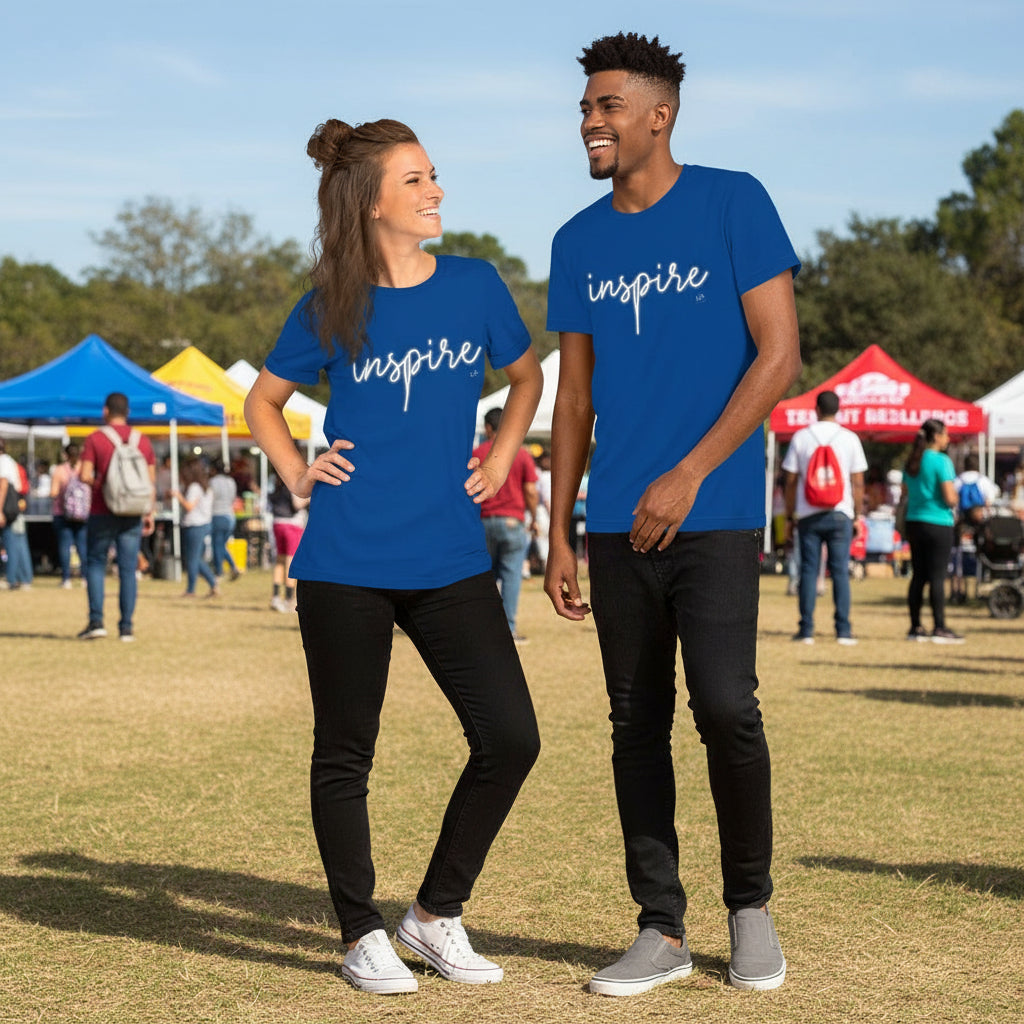Two people wearing blue 'inspire' t-shirts standing outdoors with a crowd in the background.