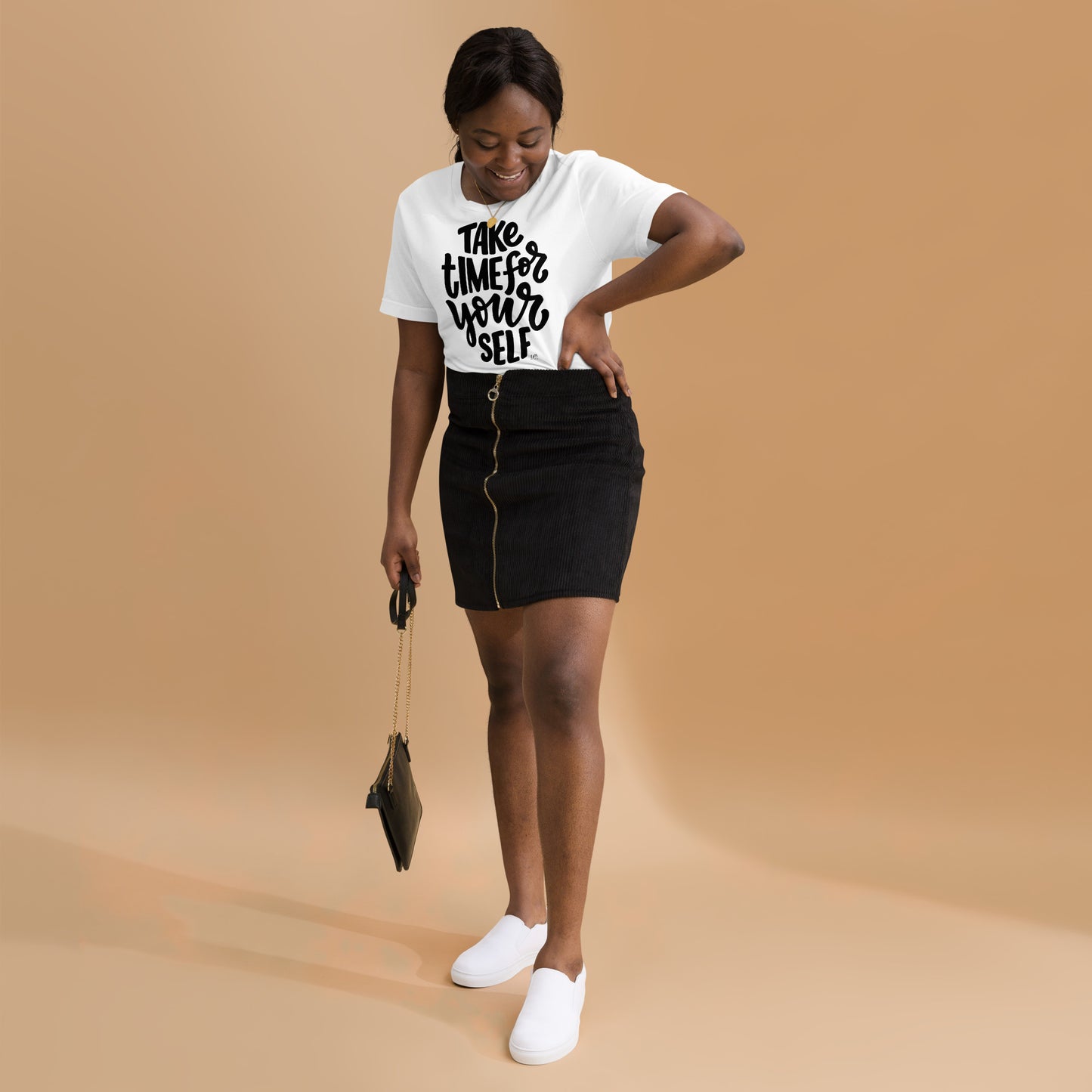 Woman wearing a white t-shirt with text and black skirt on a beige background