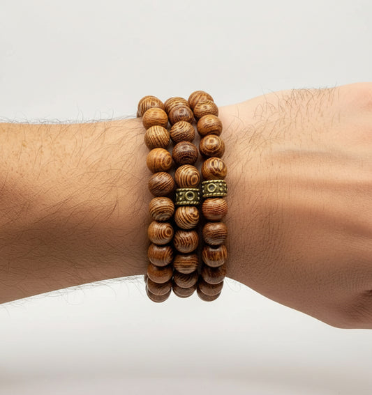 Wooden beaded bracelet with a metal clasp on a wrist against a light background