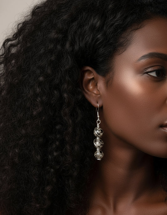 Woman wearing handmade triple spiral wrapped earrings with black and clear glass beads