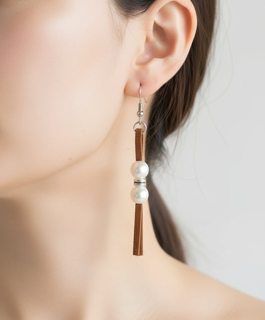 A woman wearing handmade faux leather tassel earrings with pearl accents