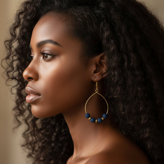 Woman wearing a gold hoop earring with blue beads on a neutral background