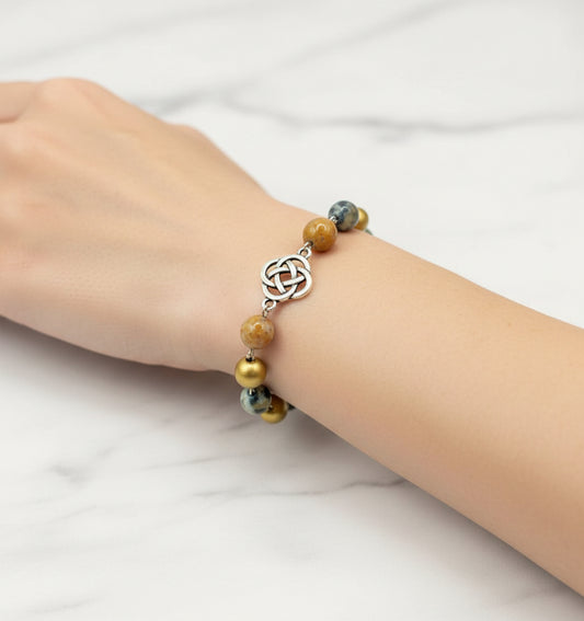 Bracelet with Celtic knot design and colorful beads on a black surface with wooden background